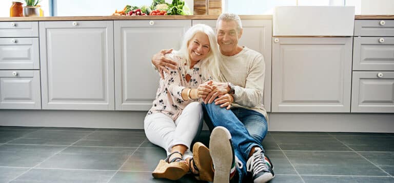 Älteres Ehepaar sitzt in der Küche auf Fliesenboden mit großen Fliesen